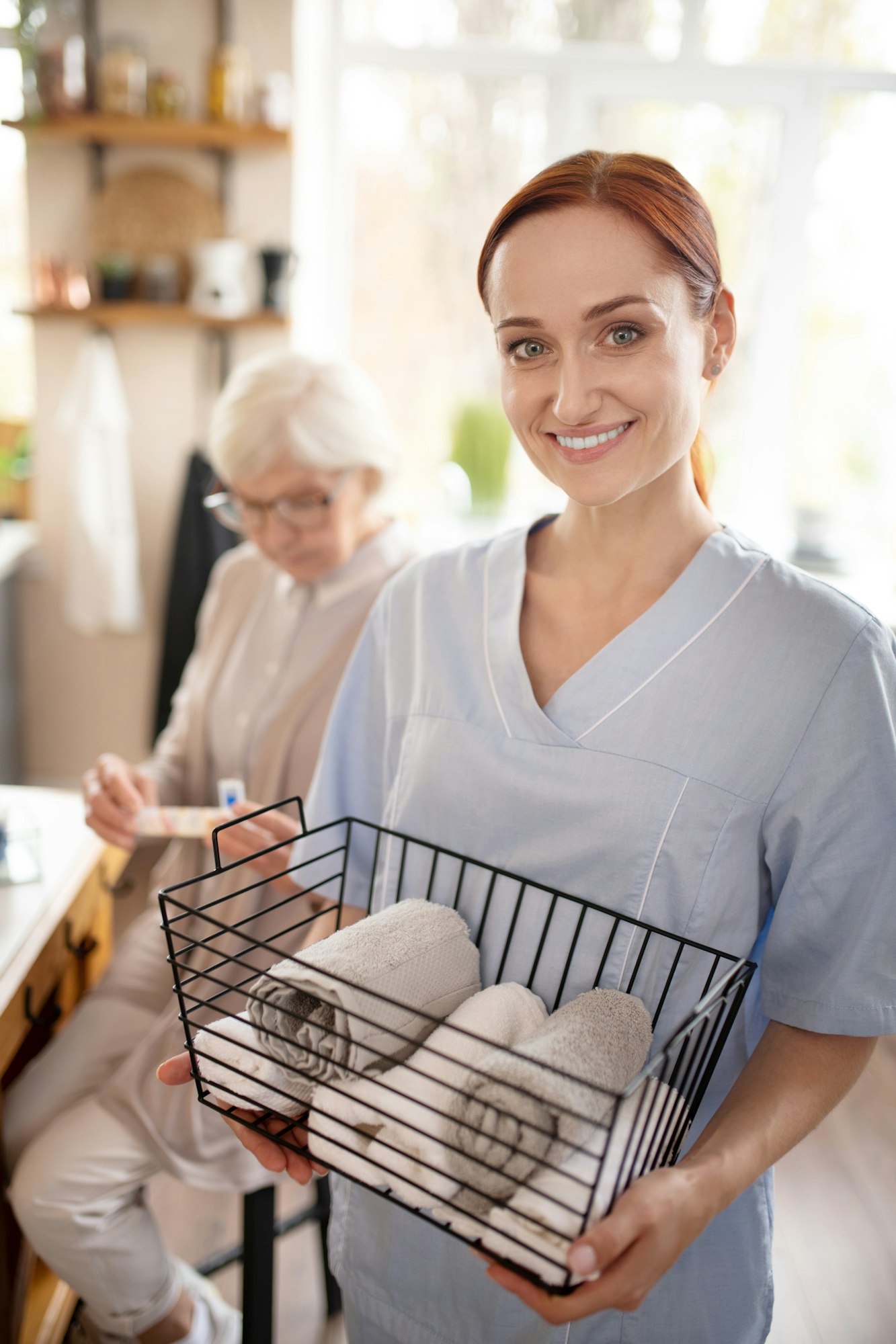 Personal female caregiver smiling after washing towels